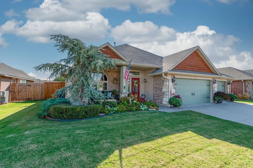 After: the same Romeo Drive home in Edmond with a freshly painted exterior and sage garage doors