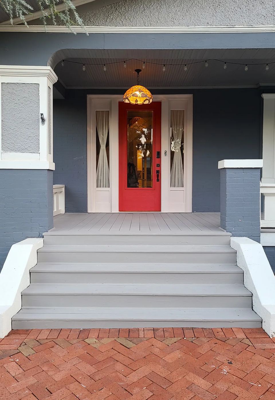 After: the same Mesta Park porch with fresh gray decking, white trim, and a red front door