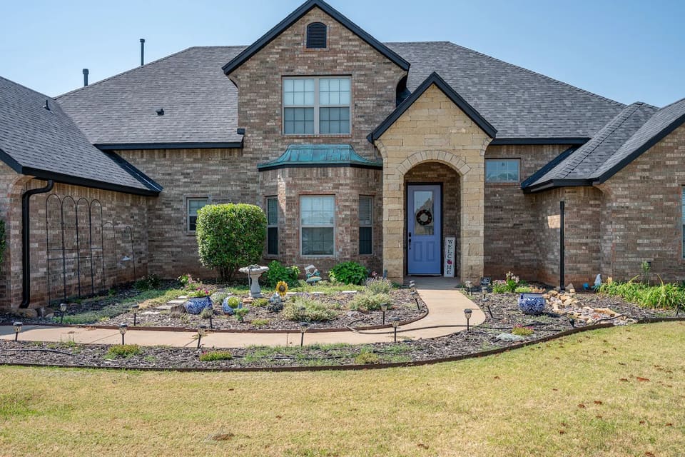 Stone entry arch in Yukon, OK framing a front door painted Awesome Violet, with Iron Ore trim on the surrounding rooflines